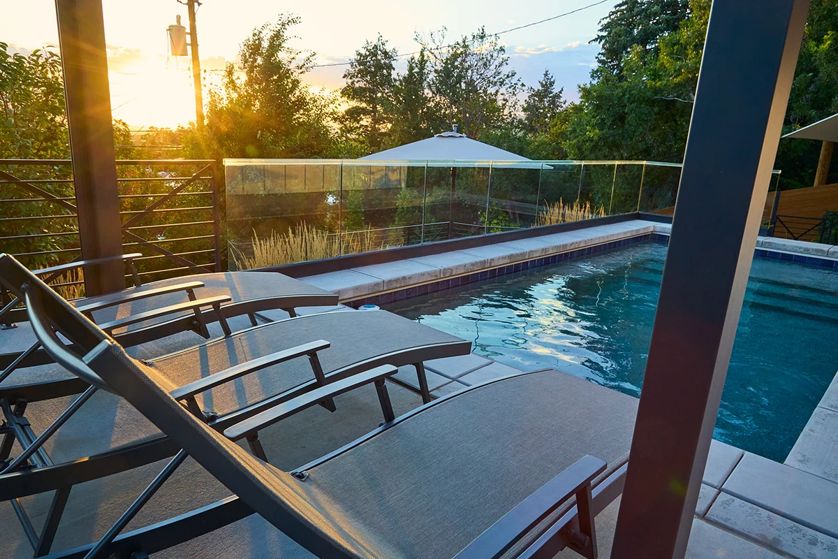 view of the swimming pool from behind three lounge chairs